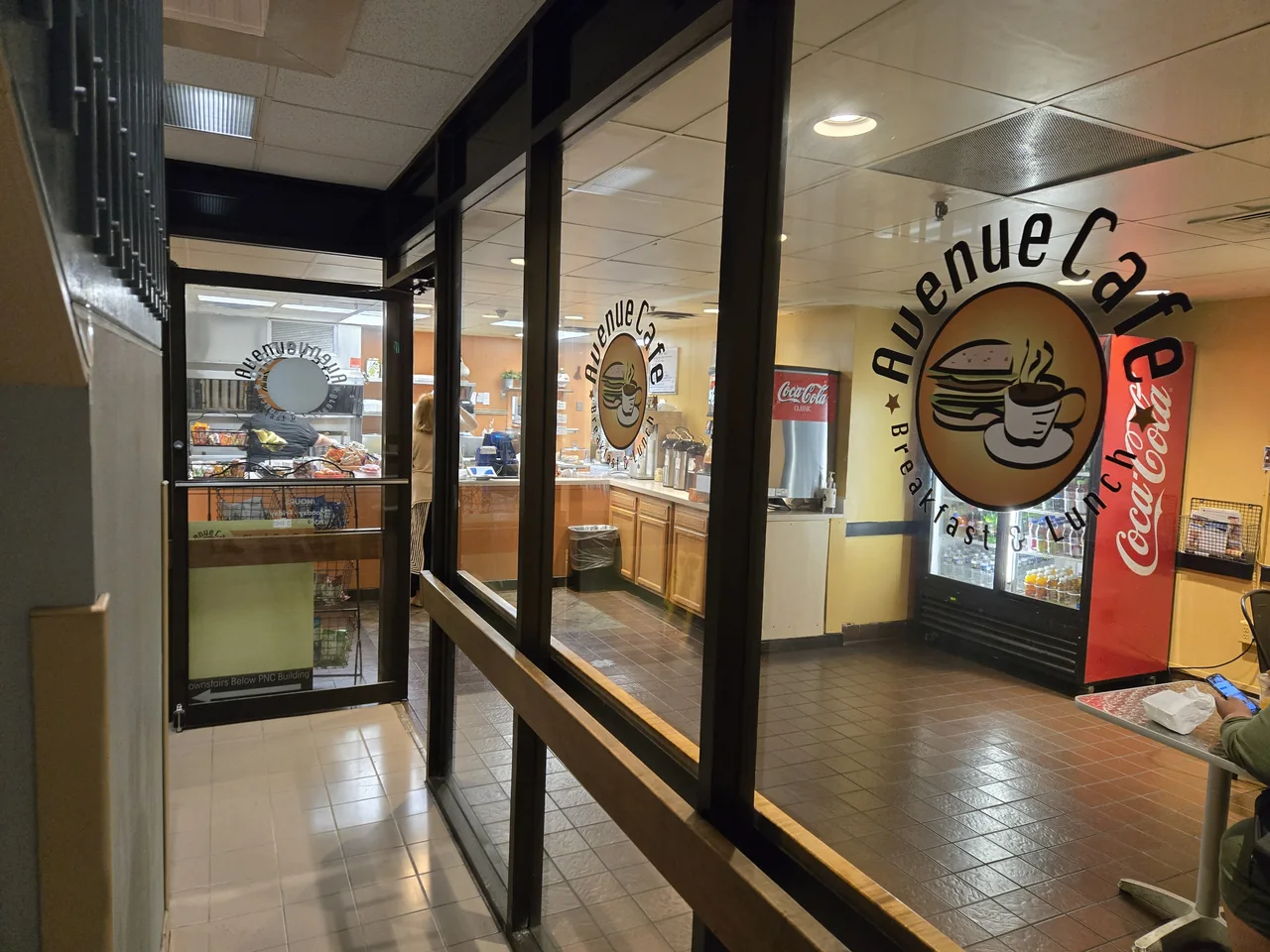 The glass entrance to Avenue Cafe inside the building, with the door on the left and cafe lettering on the right.